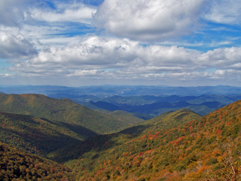 Cloud shadows race against fall colors layered against blue mountains along the Blue Ridge Parkway.