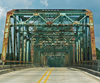 A rusty green bridge stretches over the East Pearl River in Pearlington, MS near the Louisiana state line.